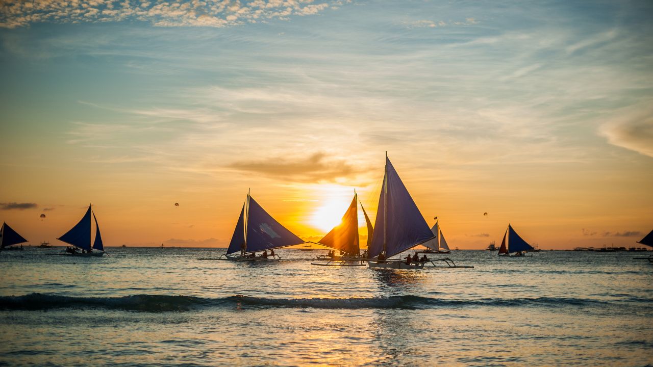 Sailboats crossing the sea at sunset in Boracay